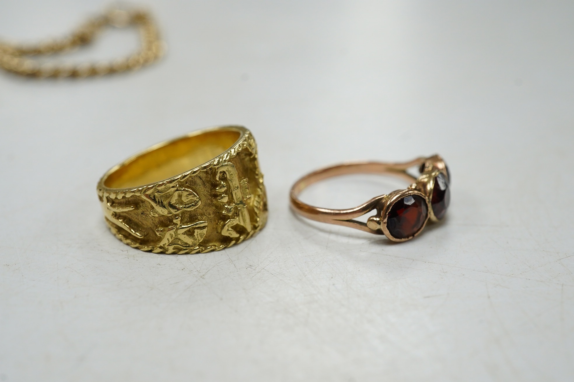 A 9ct curb link identity bracelet, with engraved inscription, 19cm, 12.5 grams, together with a yellow metal Egyptianesque ring and a yellow metal and three stone garnet set ring. Condition - fair